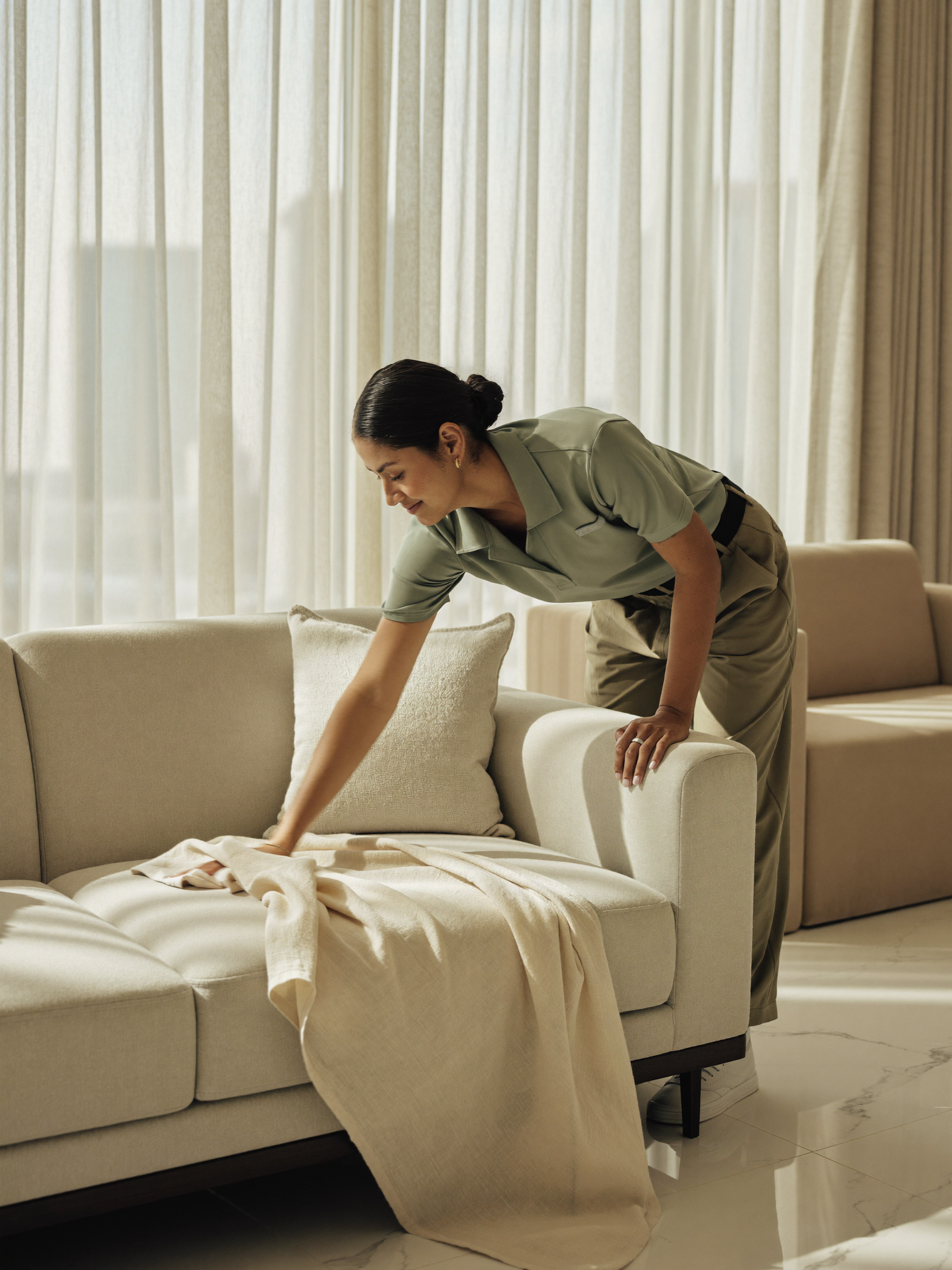 A Tip Top cleaner smoothing a throw in a pristine sunlit Sharjah living room